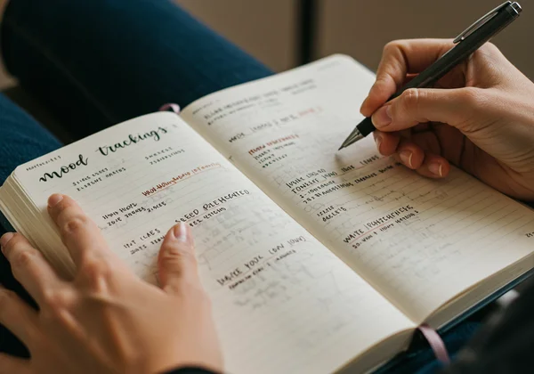 Hand writing notes in a journal to track bipolar symptoms